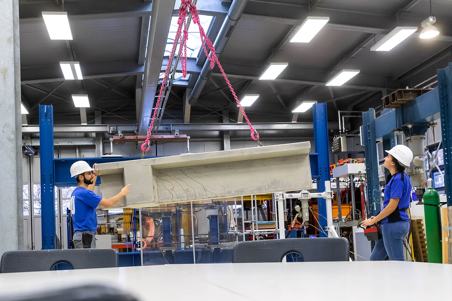 Zwei Personen an einem großen Betonbauteil in einer Halle