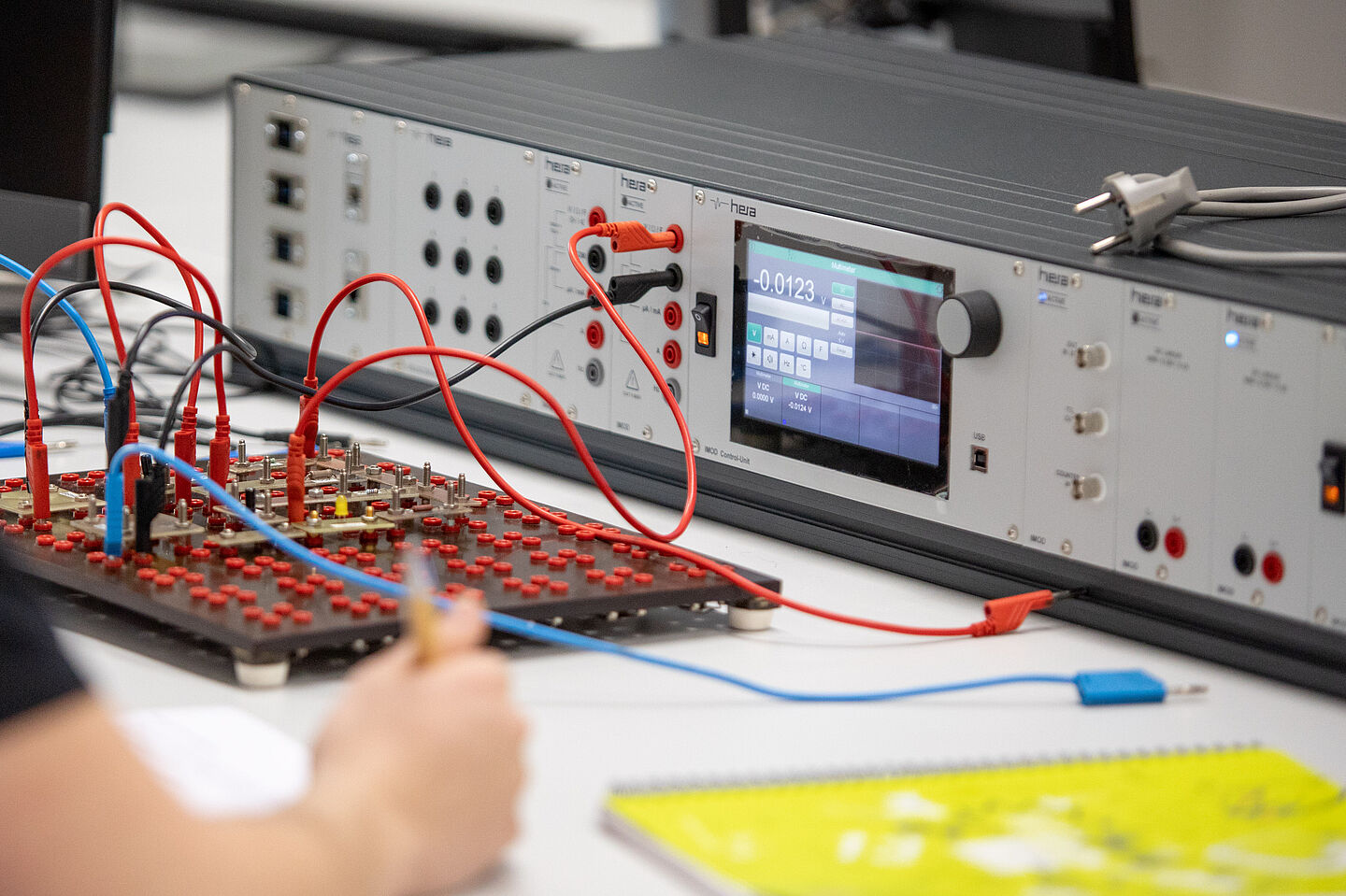 Eine Person schreibt eine Notiz über die angezeigten Werte eines elektronischen Geräts