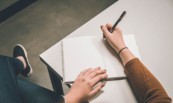 Eine Person hält Stift und Papier