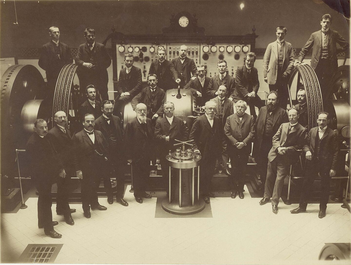 Maschinensaal der Städtischen Gewerbeschule (Quelle: HTWK Leipzig) Archivfoto von Lehrern und Schülern vor einer großen Apparatur